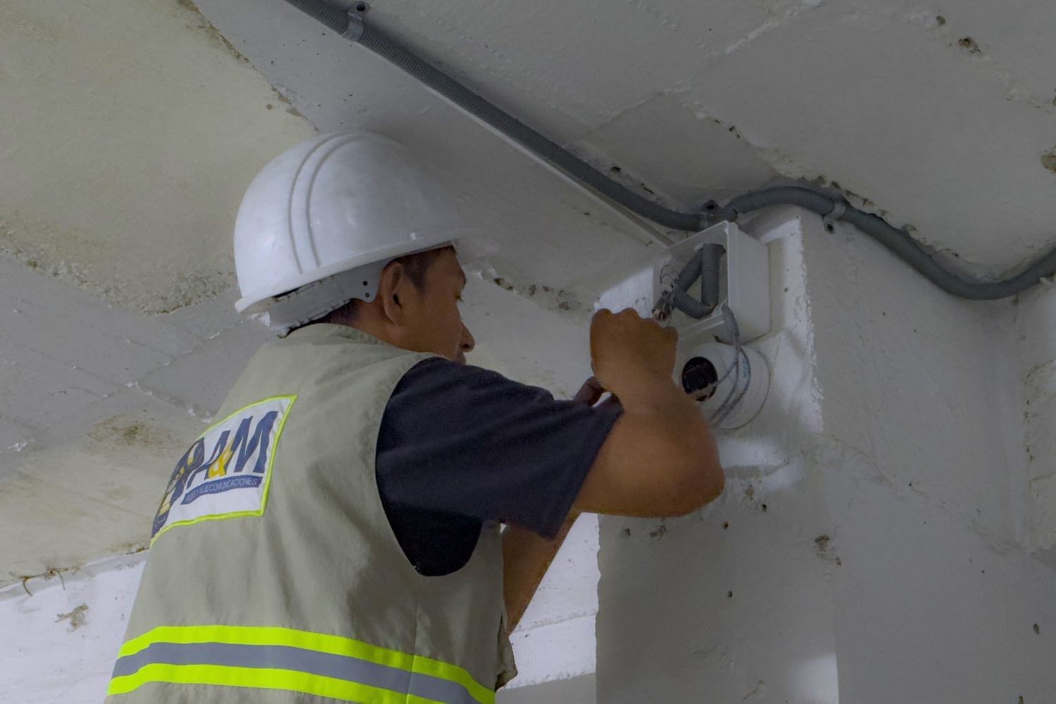 Empleado realizando el mantenimiento de una camara esta sobre una escalera